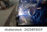 Small photo of Welding with sparks close-up. Workers in industrial uniform and welded iron mask. Close-up of a welder welding metal. A welder in a mask welds metal and sparks the metal.