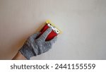 Small photo of Cleaning putty with sandpaper. Peeling off uneven surfaces on a putty wall, sanding the freshly plastered wall surface with sandpaper. The plasterer smoothest the wall with sandpaper.