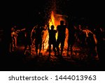People dancing around a big campfire on the beach