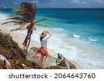 A romantic girl stands on a cliff overlooking the endless turquoise Caribbean Sea in Tulum. Paradise landscapes of Tulum on tropical coast and picturesque beach, ruins of Tulum, Mexico 