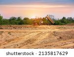 A truck is moving into sand at a ground leveling construction site., land plot for housing construction project with car tire print in rural area Land for sales landscape concept.