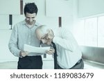 Small photo of Senior and junior office workers reviewing agreement. CEO opening eyebrows to read small print in contract. Business meeting and paperwork concept