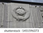 Small photo of USSR hammer and sickle emblem carved in stone. Soviet Union nation symbol on the building wall in Moscow, Russia