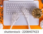 Small photo of Funny Halloween workplace with laptop flat lay. Office corporation Halloween party invitation, blogger autumn holiday background. White laptop with Halloween party decor, orange background top view