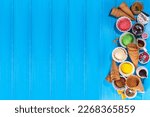 Ice cream festival background, Summer ice cream buffet with various gelato sundaes flavors. sweet toppings and sprinkles, high-colored blue wooden background to view copy space