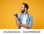 Cheerful young man in casual blue shirt posing isolated on yellow orange background, studio portrait. People emotions lifestyle concept. Mock up copy space. Holding in hand car keys, looking aside