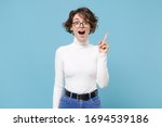 Excited young brunette woman girl in casual white clothes, eyeglasses posing isolated on pastel blue background. People lifestyle concept. Mock up copy space. Hold index finger up with great new idea