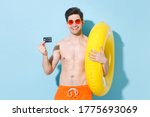 Small photo of Smiling young man guy in eyeglasses isolated on pastel blue wall background studio portrait. People summer vacation rest lifestyle concept. Mock up copy space. Hold inflatable ring credit bank cank