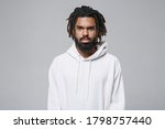 Serious attractive handsome young african american man with dreadlocks 20s in white casual streetwear hoodie posing looking camera isolated on grey color wall background studio portrait