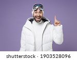 Excited skier man in white windbreaker jacket ski goggles mask hold index finger up with great new idea spend weekend winter in mountains isolated on purple background. People lifestyle hobby concept