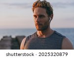 Close up young strong sporty athletic toned fit sportsman man in sports clothes earphones warm up training with music at sunrise sun dawn over sea beach outdoor on pier seaside in summer day morning.