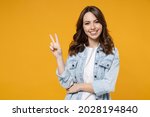Young caucasian smiling happy brunette friendly woman 20s in stylish casual denim shirt white t-shirt show victory v-sign gesture isolated on yellow background studio portrait People lifestyle concept