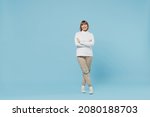 Full body size elderly cheerful caucasian smiling woman in white knitted sweater hold hands crossed folded look camera isolated on plain blue color background studio portrait. People lifestyle concept