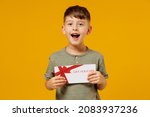 Little small smiling happy boy 6-7 years old wearing green t-shirt hold gift certificate coupon voucher card for store isolated on plain yellow background. Mother's Day love family lifestyle concept