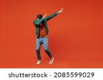 Small photo of Full size body length fun young brunet man 20s wears red t-shirt green jacket doing dab hip hop dance hands move gesture youth sign hide cover face isolated on plain orange background studio portrait.