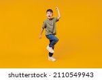 Full body little small fun happy boy 6-7 years old wearing green t-shirt do winner gesture clench fist isolated on plain yellow background studio portrait. Mother's Day love family lifestyle concept