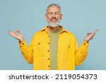 Small photo of Elderly spiritual gray-haired mustache bearded man 50s wearing yellow shirt hold spreading hands in yoga om aum gesture relax meditate try to calm down isolated on plain pastel light blue background.