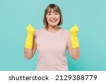 Elderly housewife woman 50s in pink t-shirt gloves doing winner gesture celebrate clenching fists say yes isolated on plain pastel light blue background studio Housekeeping cleaning tidying up concept