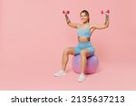 Full size young strong sporty athletic fitness trainer instructor woman wear blue tracksuit spend time in home gym sit on fitball isolated on pastel plain light pink background. Workout sport concept