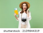 Traveler fun excited happy tourist woman in casual clothes hat camera passport tickets hold face isolated on green background Passenger travel abroad on weekends getaway. Air flight journey concept
