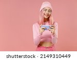 Small photo of Young gambling fun woman with dyed rose hair in rosy top shirt hat using play racing app on mobile cell phone hold gadget smartphone for pc video games isolated on plain light pastel pink background