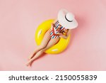 Small photo of Top view full body young woman in striped swimsuit lies on inflatable rubber ring pool read book cover face with hat isolated on plain pastel pink background. Summer vacation sea rest sun tan concept
