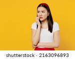 Small photo of Nervous disturb young sad woman of Asian ethnicity 20s years old wears white t-shirt looking aside biting nails isolated on plain yellow background studio portrait. People emotions lifestyle concept