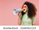 Exultant happy vivid young curly latin woman 20s wears mint t-shirt sunglasses hold scream in megaphone announces discounts sale Hurry up isolated on plain pastel light pink background studio portrait