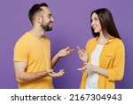 Small photo of Young smiling cheerful happy cool couple two friends family man woman together in yellow casual clothes look to each other speak talk spead hands isolated on plain violet background studio portrait