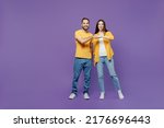 Full body young smiling happy couple two friends family man woman together in yellow casual clothes looking camera giving a fist bump in agreement isolated on plain violet background studio portrait