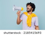 Promoter jubilant young bearded Indian man 20s years old wears white t-shirt hold scream in megaphone announces discounts sale Hurry up isolated on plain pastel light blue background studio portrait
