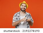 Small photo of Young smiling fun tourist man wear beach shirt hat apply sunscreen spf cream on face to protect skin from uv rays isolated on plain orange background studio. Summer vacation sea rest sun tan concept