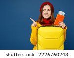 Small photo of Traveler woman wears sweater red hat yellow raincoat hold suitcase passport ticket isolated on plain dark royal blue background Tourist travel abroad in free time rest getaway Air flight trip concept
