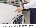 Close up man male hand customer buyer client in white shirt chooses auto wants to buy new automobile touch hood of BMW brand in showroom vehicle salon dealership store motor show indoor Sales concept