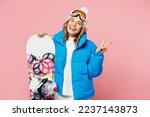 Small photo of Snowboarder smiling woman wear blue suit goggles mask hat ski padded jacket wink show victory gesture isolated on plain pastel pink background. Winter extreme sport hobby weekend trip relax concept