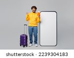 Full body traveler man wear casual clothes hold passport ticket near blank screen mobile phone valise isolated on plain grey background Tourist travel abroad in free time rest Air flight trip concept