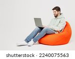 Small photo of Full body young programmer happy caucasian IT man wear mint hoody sit in bag chair hold use work on laptop pc computer isolated on plain solid white background studio portrait People lifestyle concept