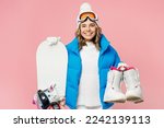 Snowboarder smiling fun woman wears blue suit goggles mask hat ski padded jacket hold snowboard boots isolated on plain pastel pink background. Winter extreme sport hobby weekend trip relax concept