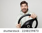 Young surprised happy fun satisfied amazed caucasian man wear mint hoody look camera hold steering wheel driving car isolated on plain solid white background studio portrait. People lifestyle concept