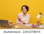 Small photo of Young happy employee business woman wear casual shirt sit work at office desk with pc laptop point fingers aside on area mockup isolated on plain yellow color background. Achievement career concept
