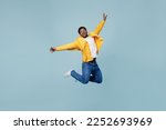 Small photo of Full body young fun man of African American ethnicity 20s wear yellow shirt jump high with outstretched hands isolated on plain pastel light blue background studio portrait. People lifestyle concept