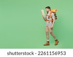 Full body side view young traveler white man carry backpack stuff mat walk look at map go isolated on plain green background Tourist leads active healthy lifestyle Hiking trek rest travel trip concept
