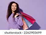 Small photo of Sideways young woman wear pullover hold in hand paper package bags after shopping look aside on area isolated on plain pastel light purple color background studio. Black Friday sale buy day concept