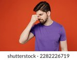 Small photo of Young tired preoccupied brunet caucasian man 30s wear casual basic purple t-shirt keep eyes closed rub put hand on nose isolated on plain orange background studio portrait. People lifestyle concept
