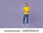 Small photo of Full body young happy fun cool caucasian man wear yellow t-shirt point index finger aside indicate on workspace area copy space mock up isolated on plain pastel light purple background studio portrait