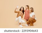 Full body women wear casual clothes with child kid girl 6-7 years old. Granny mother daughter do selfie shot mobile cell phone show v-sign isolated on plain beige background. Family parent day concept