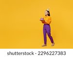 Full body sideways happy smiling fun young woman wears casual clothes hat celebrating hold in hand cake with candles walk go isolated on plain yellow background. Birthday 8 14 holiday party concept