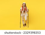 Full body smiling young woman carry bag with stuff mat hold trekking poles isolated on plain yellow background. Tourist leads active lifestyle walk on spare time. Hiking trek rest travel trip concept