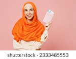 Traveler arabian woman wears orange abaya hijab hold passport ticket isolated on plain pink background Tourist travel abroad in free time rest getaway Air flight trip, uae middle eastern islam concept