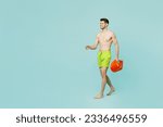 Small photo of Full body side view young lifeguard man wear green shorts swimsuit relax near hotel pool hold lifebuoy walk go look aside isolated on plain blue background. Summer vacation sea rest sun tan concept